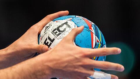 Ein Handballer hält den Spielball in den Händen.
