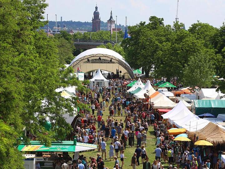 Besucher des Africa-Festivals laufen über das Gelände am Main.