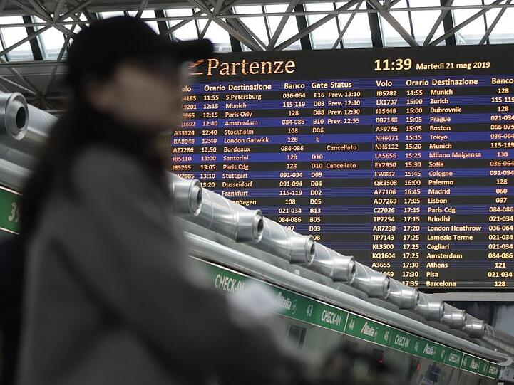 Ein Passagier steht vor einer Fluginformationstafel am Flughafen Rom-Fiumicino.
