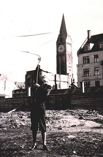 Sommer 1945. Die Münchner Altstadt liegt in weiten Teilen in Trümmern, an Wiederaufbau ist zu der Zeit noch gar nicht zu denken. Erst mal gilt es, die Versorgung in der Stadt zu sichern, was schwierig genug ist. Vor allem Kinder und Teenager freilich können dieser Trümmerzeit durchaus was abgewinnen. Die ganze Stadt &ndash; ein einziger Abenteuerspielplatz. Auf dem großen Foto sehen wir AZ-Leser Gerhard Lutzeier unmittelbar nach dem Krieg. Es zeigt ihn, wie er auf einem Trümmerfeld sein Lasso schwingt. Im Hintergrund sieht man den Turm der Kreuzkirche. &bdquo;Ich war 15 Jahre alt und Mitglied im Cowboy-Club in München&ldquo;, schreibt uns der Leser. &bdquo;Wir wohnten damals in der Josephspitalstraße im Hause Schachinger, gegenüber der Kreuzkirche. Dort, wo ich stehe und Lasso drehe, ist jetzt das Stadtsteueramt.&ldquo; Das kleine Foto oben zeigt die Kreuzkirche, gezeichnet von Gerhard Lutzeier im Jahr 1945.