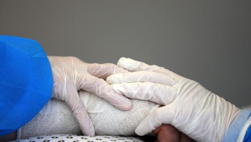 Im Infektionszimmer für Covid-19-Patienten auf der Interdisziplinären internistischen Intensivtherapiestation (ITS) der Universitätsmedizin Rostock halten Pflegekräfte die Hand eines Patienten im künstlichen Koma.