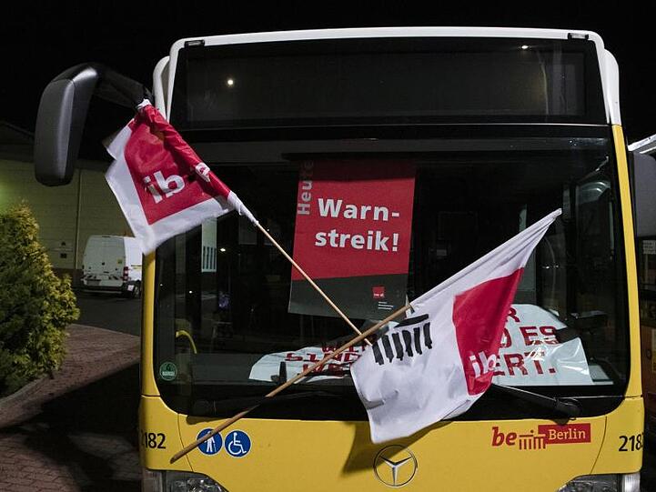 "Warnstreik" steht auf dem Plakat an einem Bus, der in der Zufahrt zum Betriebshof der Berliner Verkehrsbetriebe (BVG) an der Siegfriedstraße steht.