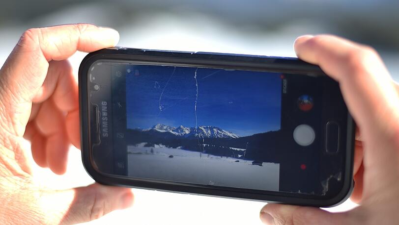 Gerold: Eine Frau fotografiert mit ihrem Smartphone den mit Eis bedeckten Geroldsee vor dem Karwendel-Gebirge. Gerold: Eine Frau fotografiert mit ihrem Smartphone den mit Eis bedeckten Geroldsee vor dem Karwendel-Gebirge.