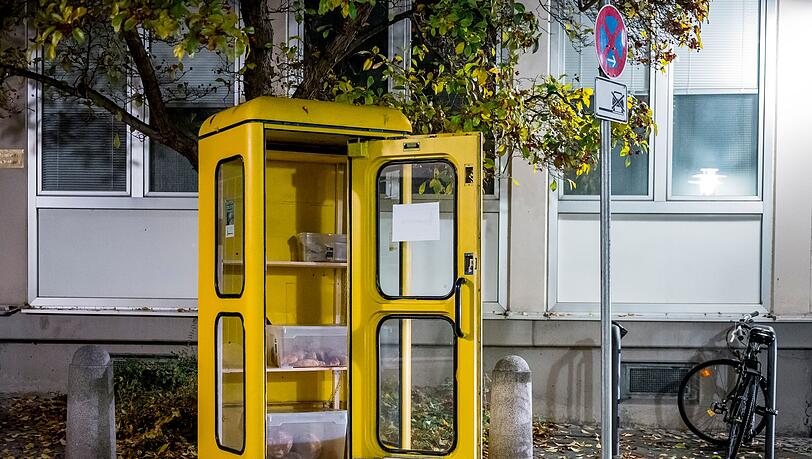 Eine "Foodsharing"-Station in einer gelben Telefonzelle ist mit Brötchen und Borten befüllt.