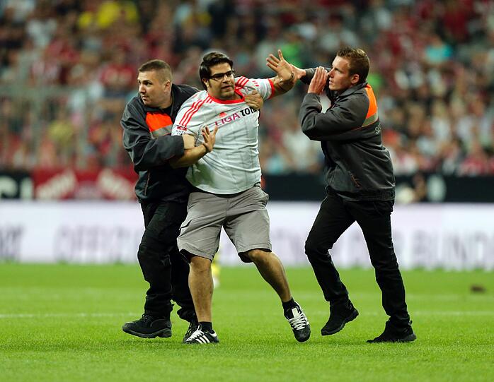 Er rennt in der 55. Minute auf den Platz und sorgt kurz für Aufsehen: Der Bayern-Fan und Flitzer wird von den Sicherheitskräften aber schnell gestellt.