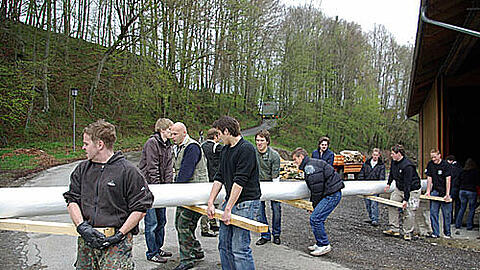 Knochenarbeit: Das 18-köpfige "Antenne"-Team trägt den Maibaum aus der Scheune.