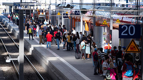 Reisende stehen am Samstagvormittag am Münchner Hauptbahnhof auf einem Bahnsteig.