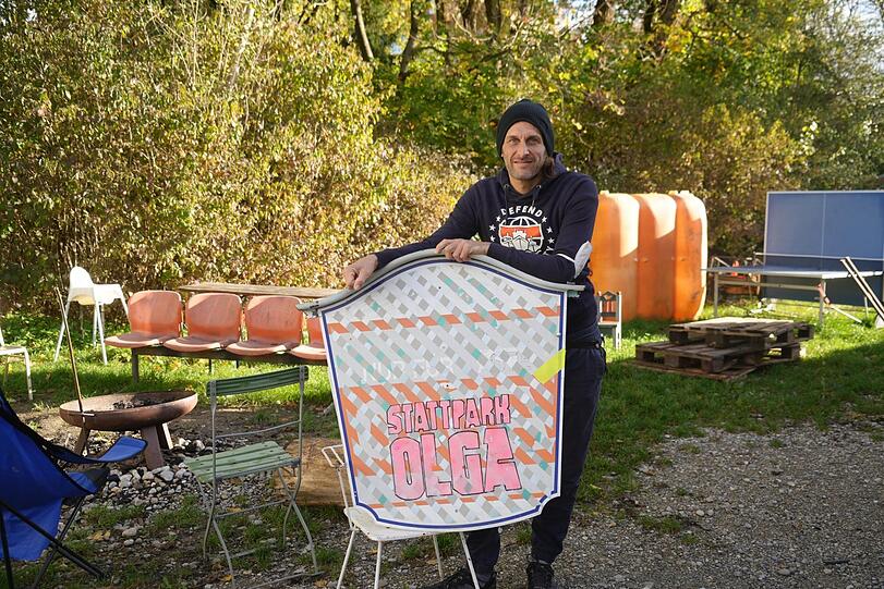 Karuna mit einem Schild des Projekts. Hinter ihm: der Grillplatz.
