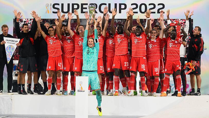 Münchens Torwart Manuel Neuer präsentiert den Pokal vor der Mannschaft auf dem Podium.