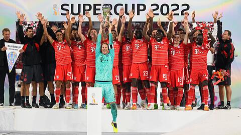 Münchens Torwart Manuel Neuer präsentiert den Pokal vor der Mannschaft auf dem Podium.