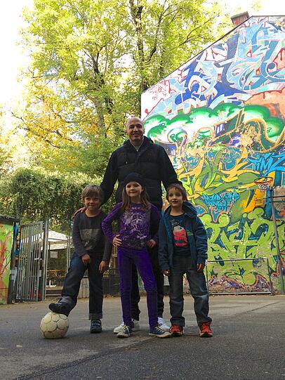 Aygün zusammen mit drei Kindern, die den Bolzplatz an der Glockenbachwerkstatt häufig besuchen.