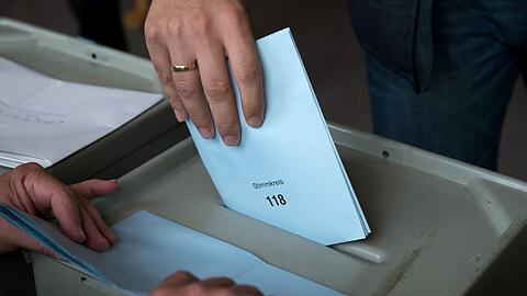 Ein Mann wirft in Ingolstadt (Bayern) seinen Stimmzettel zur Landtagswahl in die Wahlurne.