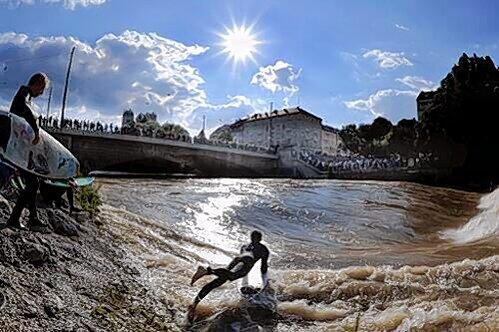 Ein so genannter Flußsurfer stürzt sich mit seinem Surfbrett in die durch Hochwasser angestiegene Isar.