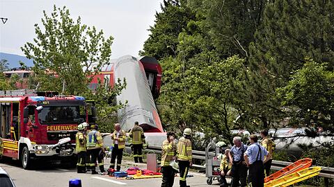 Einsatzkräfte stehen in der Nähe des umgekippten Waggons.