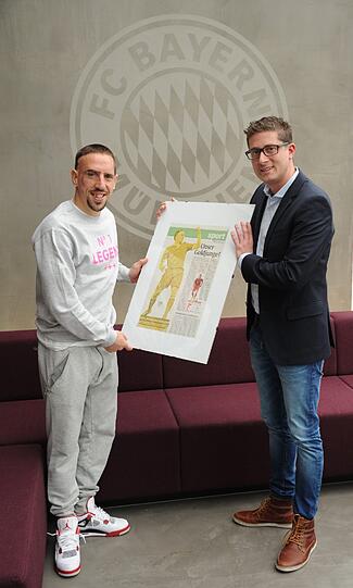 Marco Fenske, stellvertretender Sportchef der Abendzeitung, überreicht Ribéry die AZ-Sportseite vom Tag der Weltfußballer-Wahl. Sie zeigt den Franzosen als Gold-Statue, daneben steht: Unser Goldjunge.