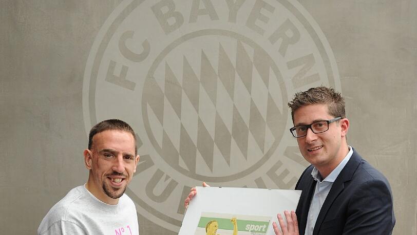 Marco Fenske, stellvertretender Sportchef der Abendzeitung, überreicht Ribéry die AZ-Sportseite vom Tag der Weltfußballer-Wahl. Sie zeigt den Franzosen als Gold-Statue, daneben steht: Unser Goldjunge.