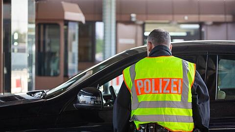 Ein Beamter der Bundespolizei kontrolliert an einem Grenzübergang einen Autofahrer.