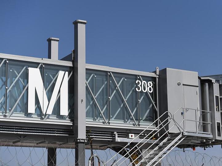 Das Logo des Münchner Flughafens ist an einer Fluggastbrücke auf dem Flughafen in München zu sehen. Foto: Andreas Gebert/Archivbild