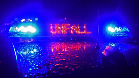 Während einer Unfallaufnahme spiegelt sich der Schriftzug "Unfall" auf dem Dach eines Polizeiwagens.