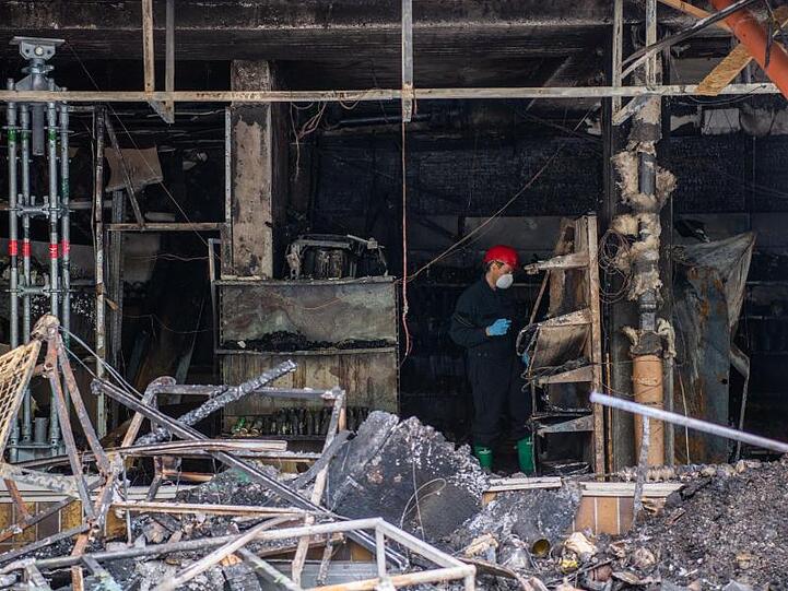 Ein Brandermittler in der Ruine eines attackierten türkischen Geschäftes in Waldkraiburg. Foto: Lino Mirgeler/dpa/Archivbild