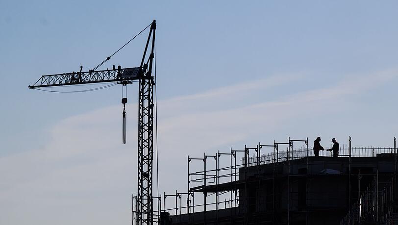 Bauarbeiter stehen auf der Baustelle eines Mehrfamilienhauses.