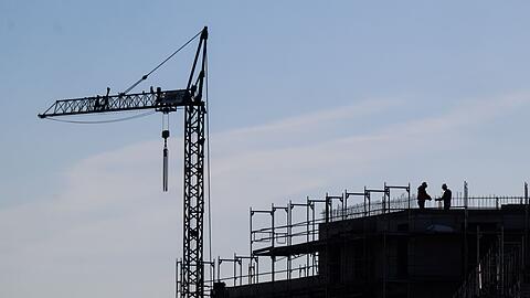 Bauarbeiter stehen auf der Baustelle eines Mehrfamilienhauses.