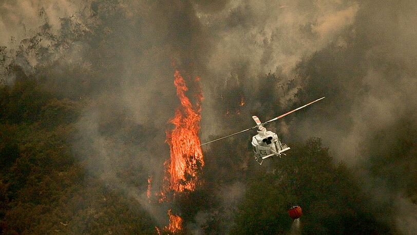 Ein Löschhubschrauber wirft Wasser über einem Feuer in der spanischen Provinz Ourense ab.