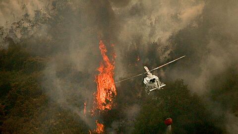 Ein Löschhubschrauber wirft Wasser über einem Feuer in der spanischen Provinz Ourense ab.