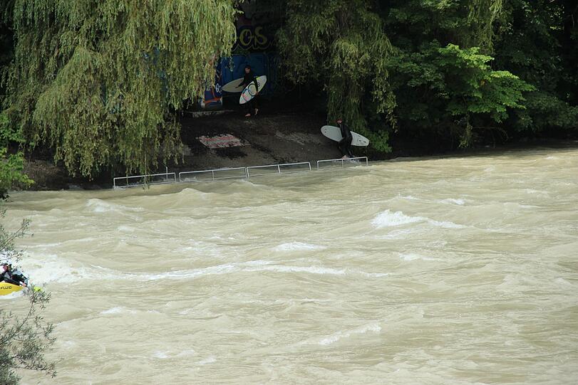 Hochwasser für die einen, perfekte Wellen für die anderen. Waghalsig tummeln sich Sportler in der Isar.