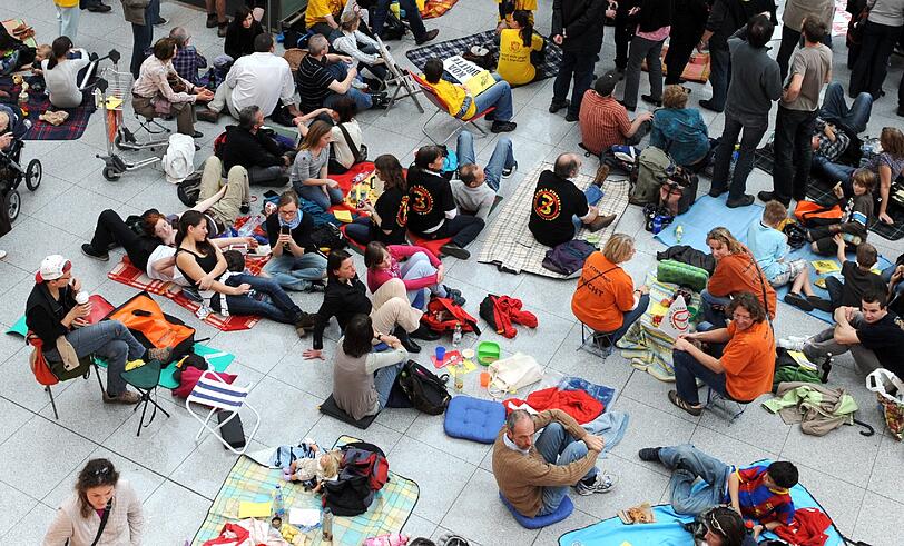 Gegen Fluglärm demonstrierende Demonstranten picknicken am Samstag (24.03.12) am Flughafen Franz-Josef-Strauss in einem Teil der Abflughalle des Terminal 2.