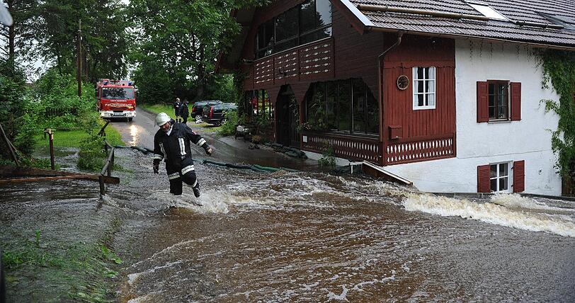 Ein Feuerwehrmann watet bei Rott (Oberbayern) im Kreis Landfsberg/Lech am Donnerstag (30.06.2011) über eine überflutete Straße.