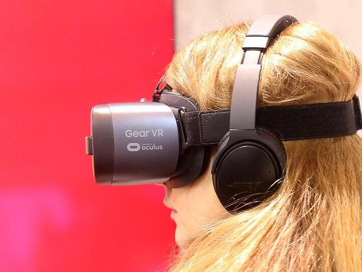 Eine Messebesucherin schaut sich durch eine 3-D-Brille Bilder an. Foto: Roland Weihrauch/dpa/Archivbild