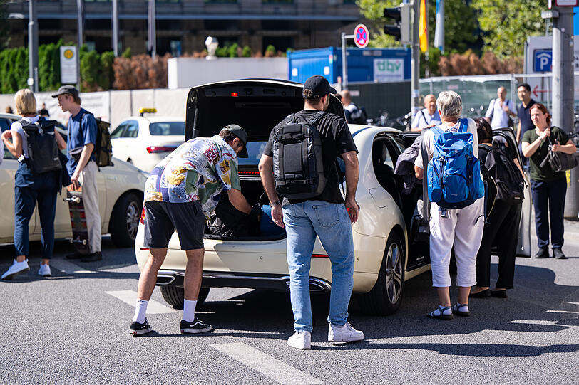 Reisende verladen ihr Gepäck vor dem Münchner Hauptbahnhof in ein Taxi.