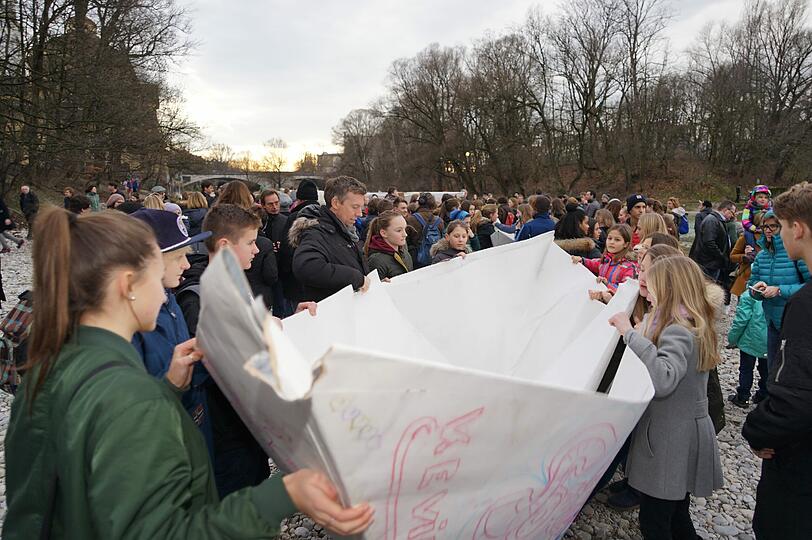 130 Firmlinge der Katholischen Jugendstelle Innenstadt hatten die fünf Schiffe unter Anleitung des Kölner Künstlers Frank Bölter gefaltet und zu Fuß in die Nähe der Muffathalle getragen.