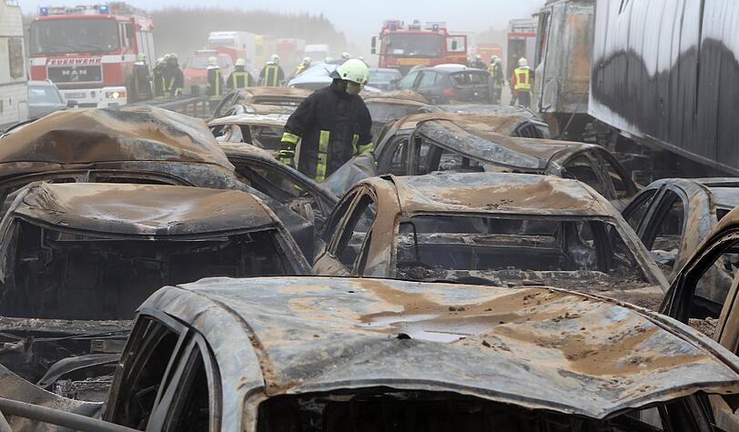 Feuerwehrleute sind am Freitag auf der Autobahn A19 bei Kavelstorf in der Nähe von Rostock bei einer Massenkarambolage im Einsatz. Bei einem Sandsturm fuhren in beiden Fahrtrichtungen Dutzende Fahrzeuge und LKW ineinander und brannten teilweise aus.