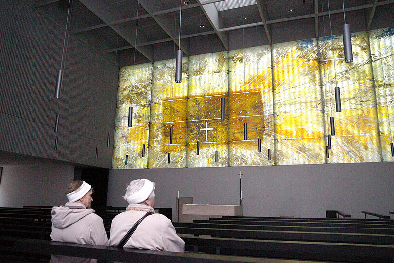 Zwei Besucher der Kirche Sankt Florian, die in der Messestadt liegt, schauen sich
das Glasbild hinter dem Altar an. &bdquo;Ein Erlebnis&ldquo;, sagen unsere Bürgerreporter.