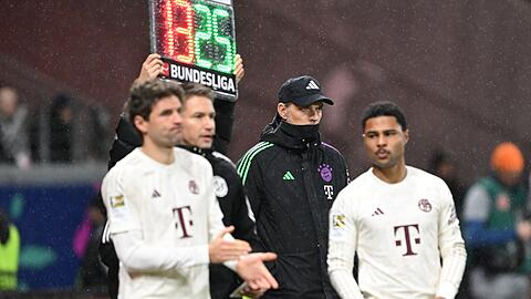 Münchens Trainer Thomas Tuchel steht zwischen Thomas Müller (l) und Serge Gnabry während des Spiels.