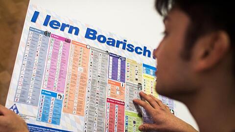 Ein Mann liest die Sprachtafel "I lern Boarisch". Foto: Alexander Heinl/dpa/Archivbild