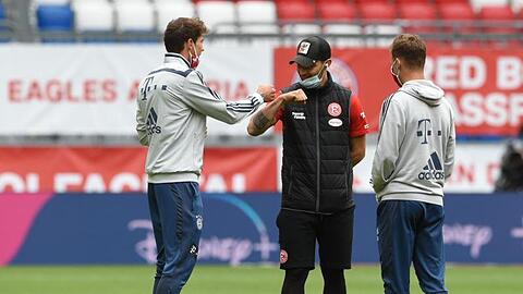 Münchens Spieler und ein Düsseldorfs Spieler (M) begrüßen sich vor dem Spiel. Foto: Christof Stache/AFP/Pool/dpa