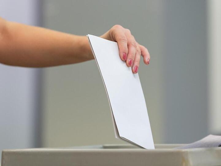 Eine Wählerin wirft bei der Stimmabgabe ihren Wahlzettel in eine Wahlurne.
