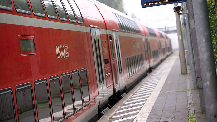Ein doppelstöckiger Regionalzug der Deutschen Bahn fährt durch einen Bahnhof.