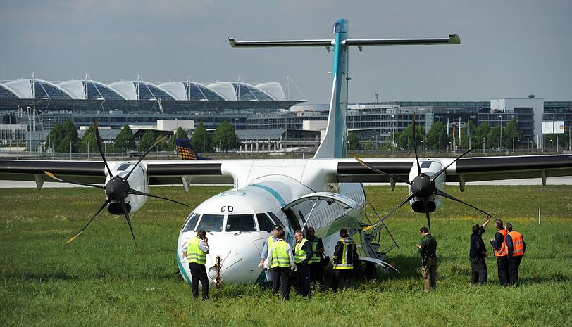 Mitarbeiter des Flughafens in München betrachten die Maschine der italienischen Fluggesellschaft, die am Donnerstag auf dem Münchner Flughafen notlanden musste. Das Flugzeug mit 62 Menschen an Bord hatte kurz nach dem Start in Richtung Venedig umdrehen müssen, weil sich Rauch in der Kabine entwickelt hatte. Bei der Landung wurden fünf Personen leicht verletzt, die Maschine kam neben der Landebahn zum Stehen.