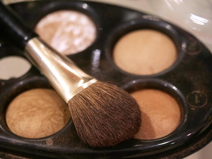 Ein Pinsel und eine Palette mit Gesichtspuder bzw. Make-Up in Puderform. Foto: Bernd Thissen/dpa/Symbolbild