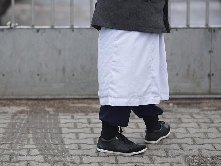 Ein Mann in traditioneller Bekleidung steht vor einem Versammlungsort der Salafisten in Berlin.