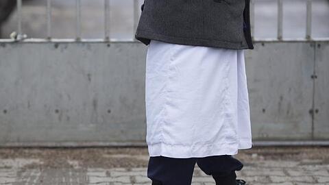 Ein Mann in traditioneller Bekleidung steht vor einem Versammlungsort der Salafisten in Berlin.
