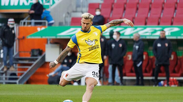 Niklas Dorsch in einem Trikot in den Landesfarben der Ukraine und mit dem Schriftzug „Friedensstadt Augsburg“.