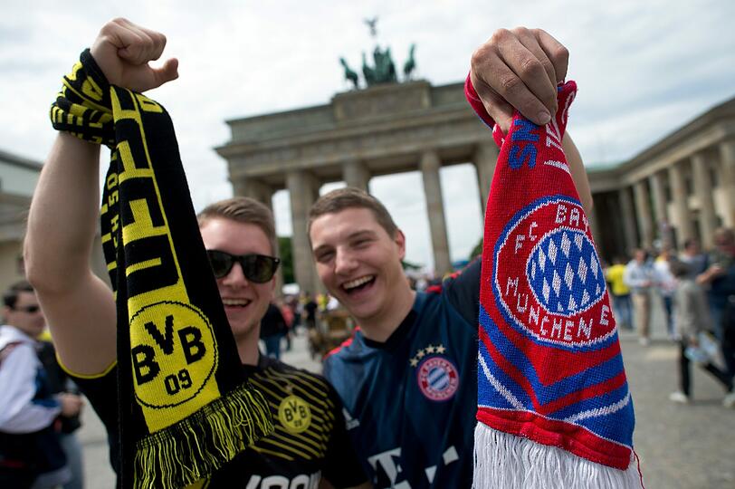 BVB-Fan Richard (l) und Bayern-Fan Randy stehen in Berlin vor dem Brandenburger Tor.