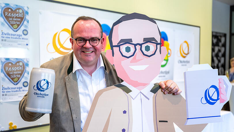 Wiesn-Chef Clemens Baumgärtner posiert mit dem Pappaufsteller seines Avatars aus "Oktoberfest – The official game".