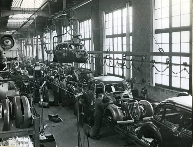 Eine Karosserie schwebt über dem Fließband, bereit, von den Arbeitern auf das Chassis geschraubt zu werden &ndash; so wurde 1938 in Chemnitz der Wanderer W 24 montiert.