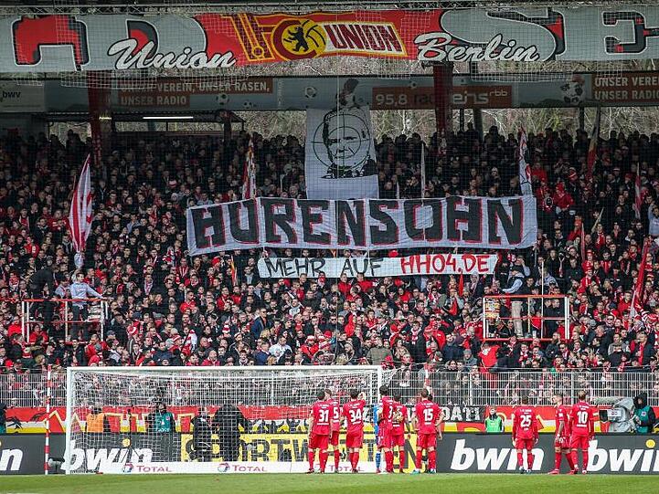 Unions Fans auf der Waldseite zeigen ein Banner mit dem Abbild von Dietmar Hopp im Fadenkreuz.